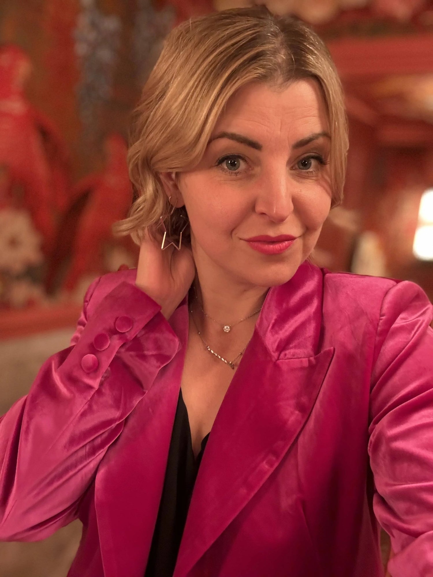 Woman wearing a bright pink jacket indoors with a blurred background