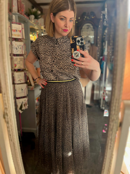 Person taking a mirror selfie wearing a patterned top and skirt in a room.