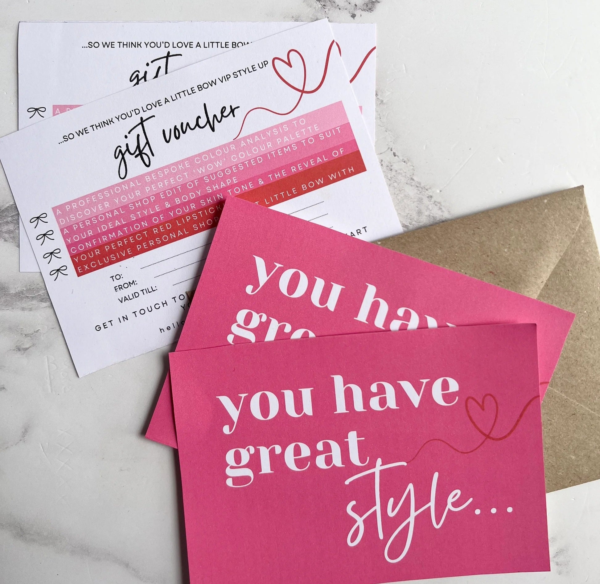 Pink cards with text and an envelope on a marble surface