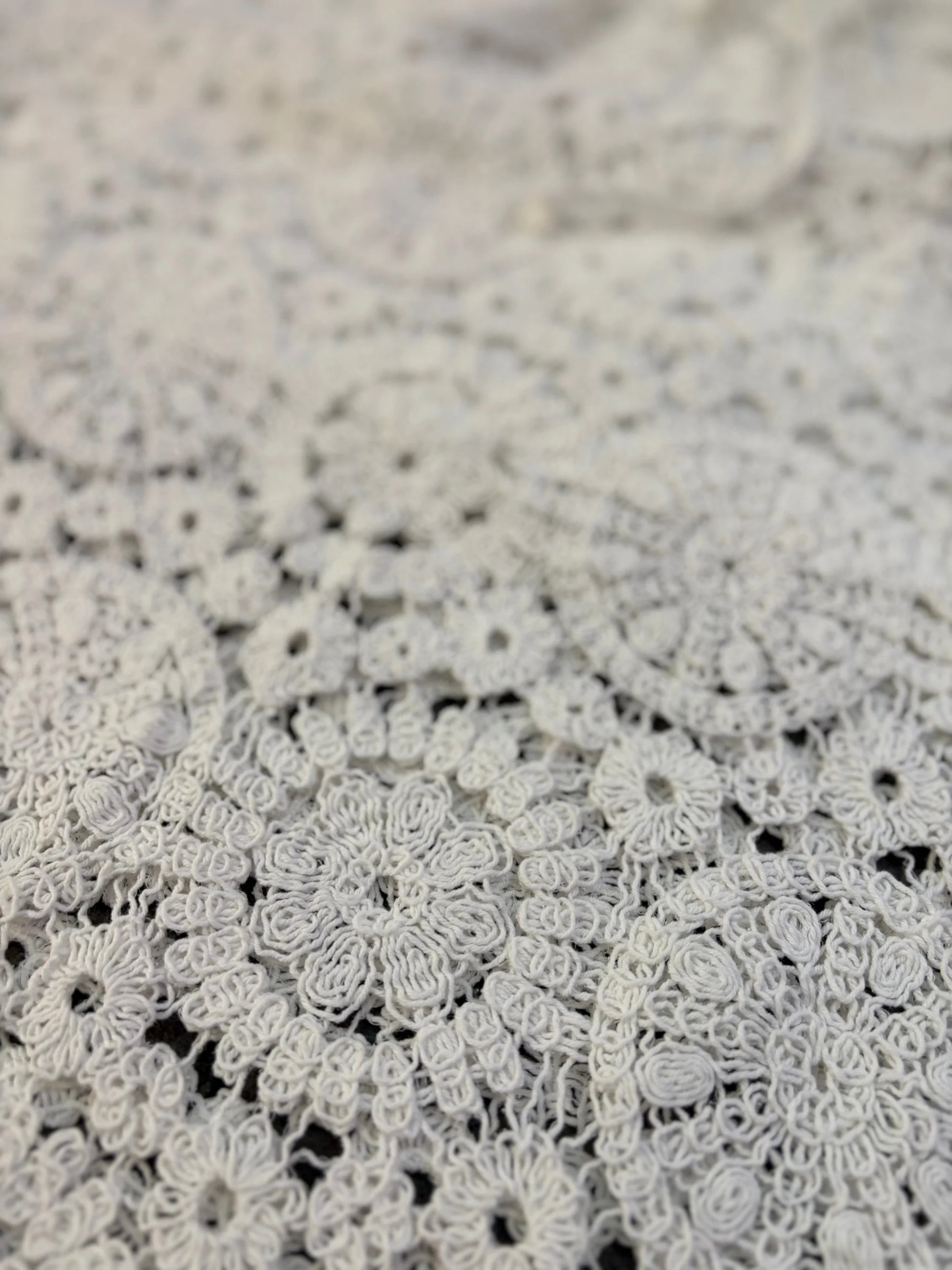 Close-up of intricate white lace fabric on a textured beige background