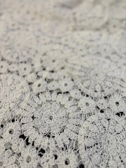 Close-up of intricate white lace fabric on a textured beige background