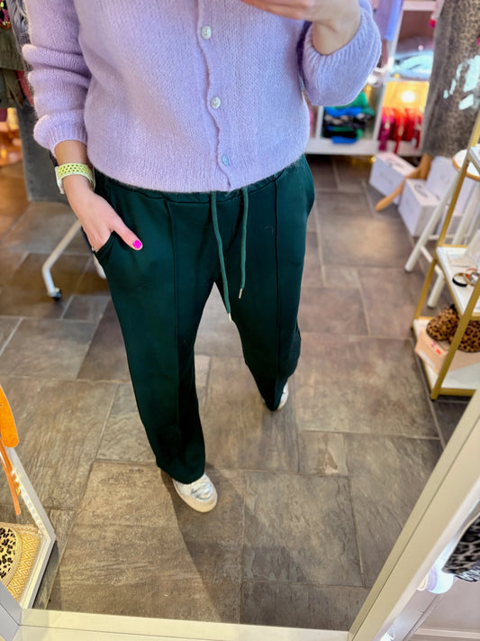 Person wearing a light purple sweater and dark green pants in a store setting.