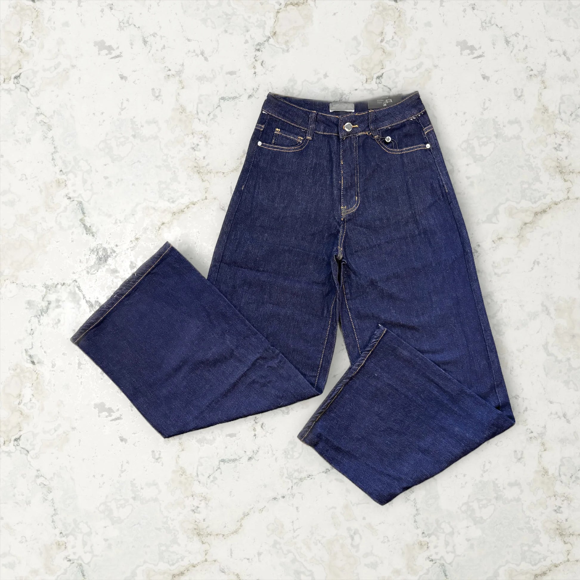 Pair of dark blue jeans on a light marble surface