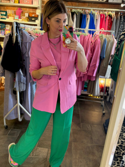 Person wearing a pink blazer and green pants in a clothing store.