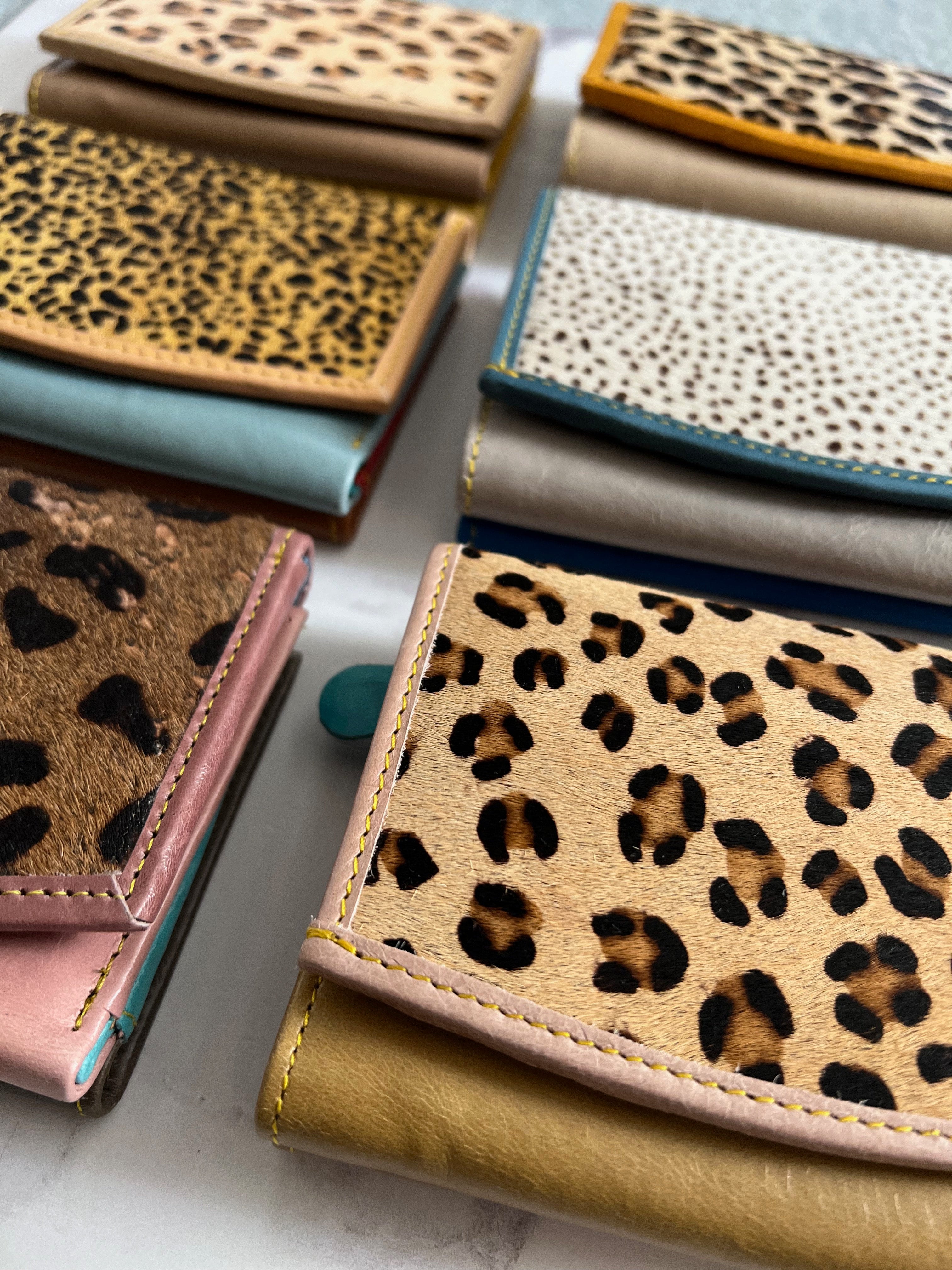 Collection of small wallets with leopard print and other patterns on a light surface.
