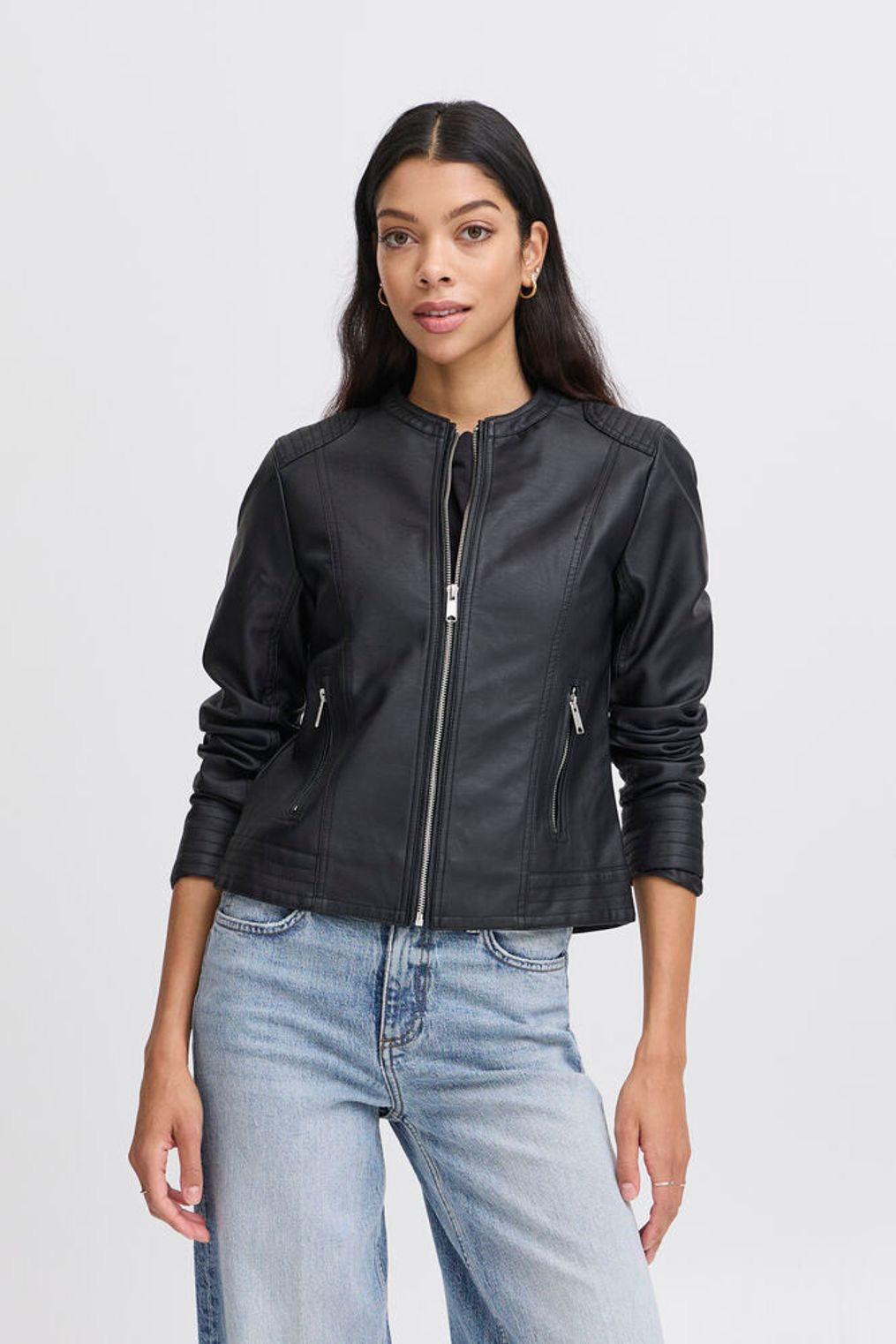 Woman wearing a black leather jacket and light blue jeans on a white background