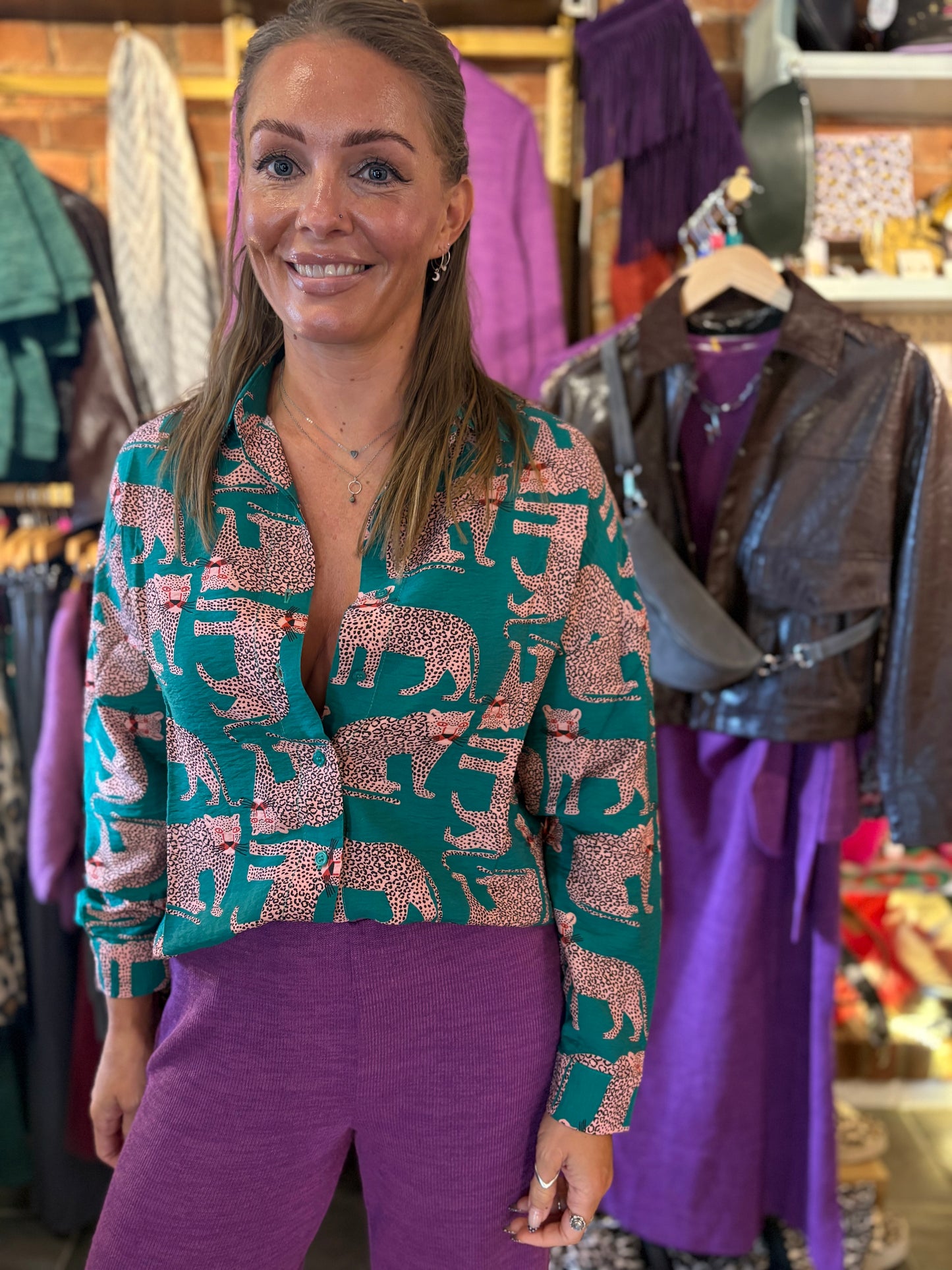 Woman wearing a cheetah print patterned blouse and purple pants in a clothing store.
