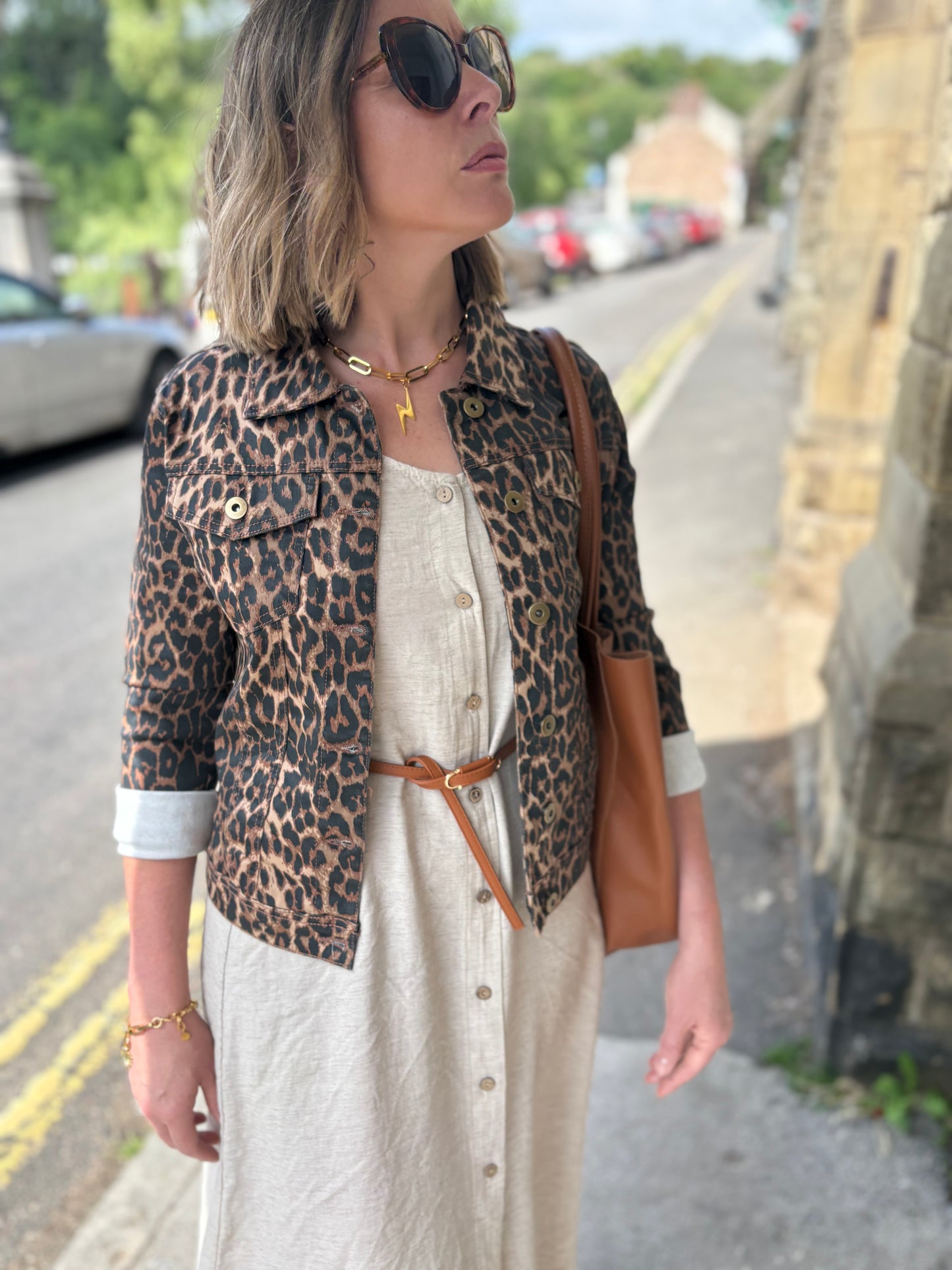 Woman wearing a leopard print jacket and sunglasses on a street.