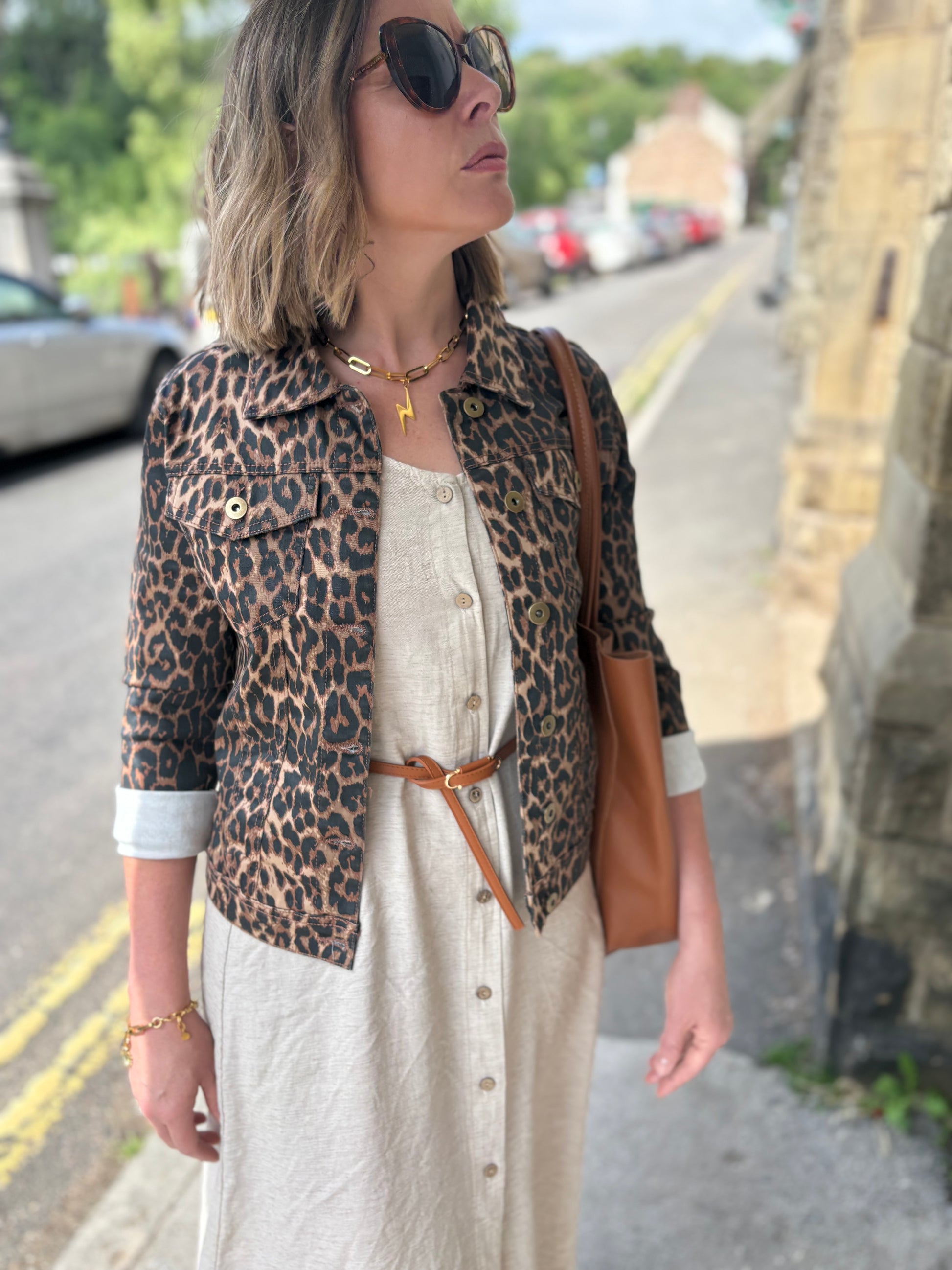 Woman wearing a leopard print jacket and sunglasses on a street.