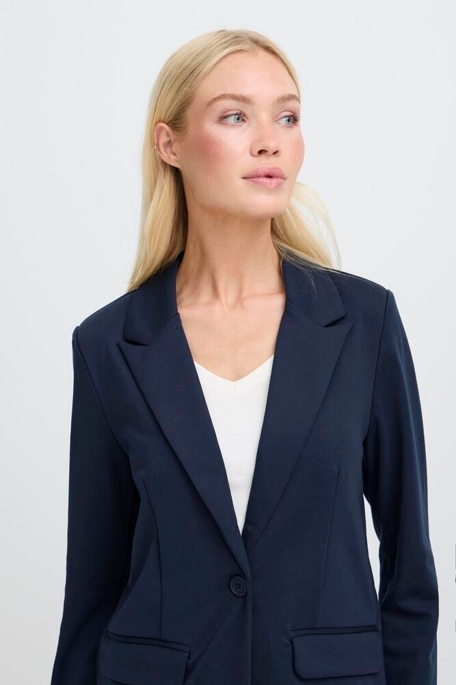 Woman wearing a navy blazer over a white top on a light gray background