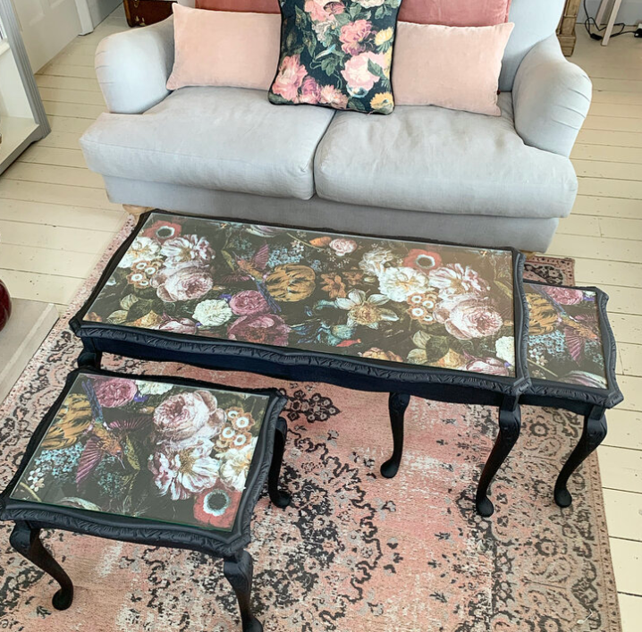 Floral-patterned coffee table and ottoman set on a rug with a sofa in the background.