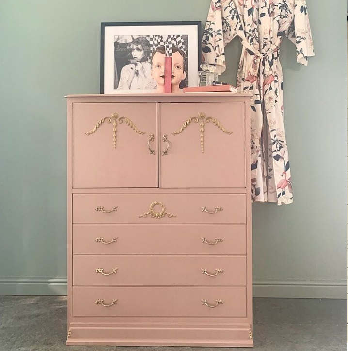 Pink dresser with gold accents against a gray wall