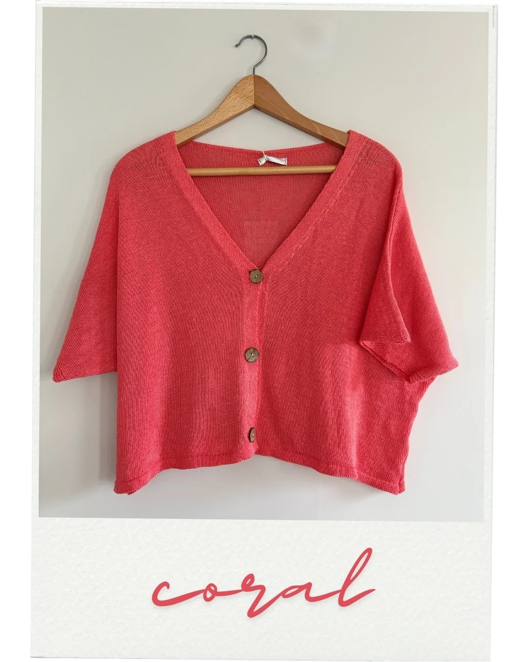 Red cardigan on a hanger with 'coral' text below