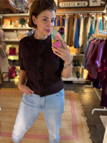Woman taking a mirror selfie wearing a burgundy top and light blue jeans in a clothing store.
