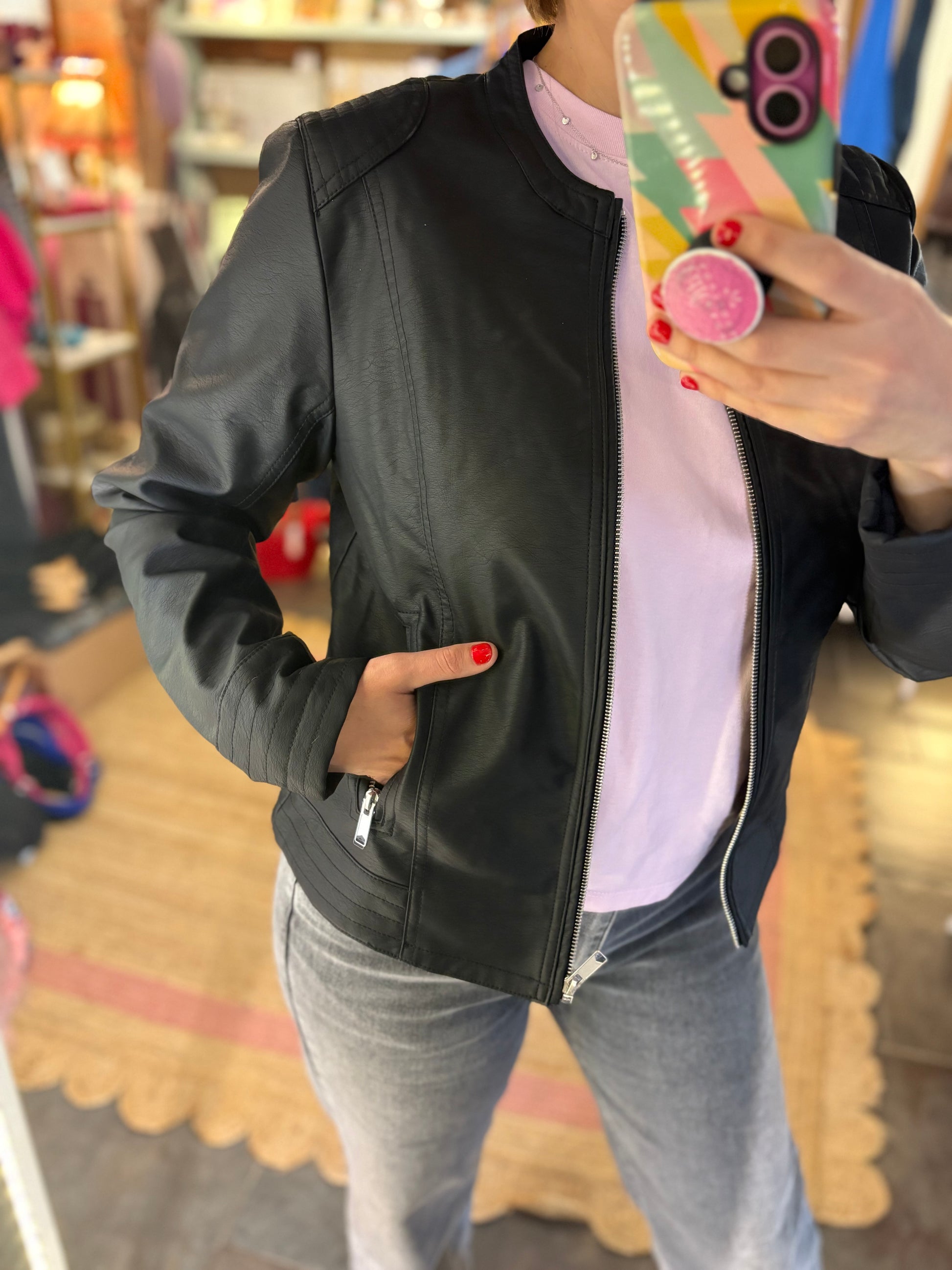 Person wearing a black jacket and grey trousers, taking a mirror selfie.