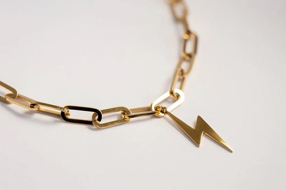 Gold chain necklace with a lightning bolt pendant on a light gray background