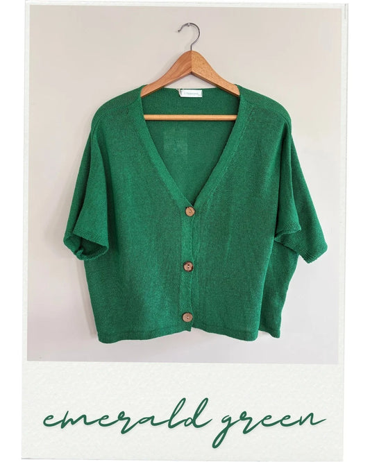 Green cardigan on a hanger with 'emerald green' text below.