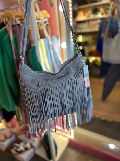 Grey fringe suede handbag with a tag on a rack in a store