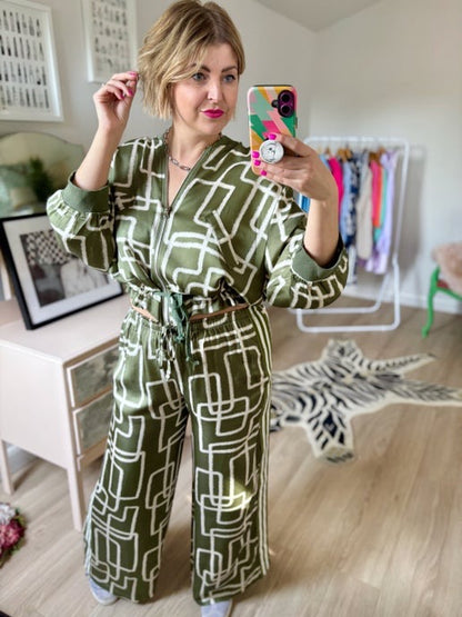 Woman taking a mirror selfie wearing a green patterned outfit in a room with a zebra rug.