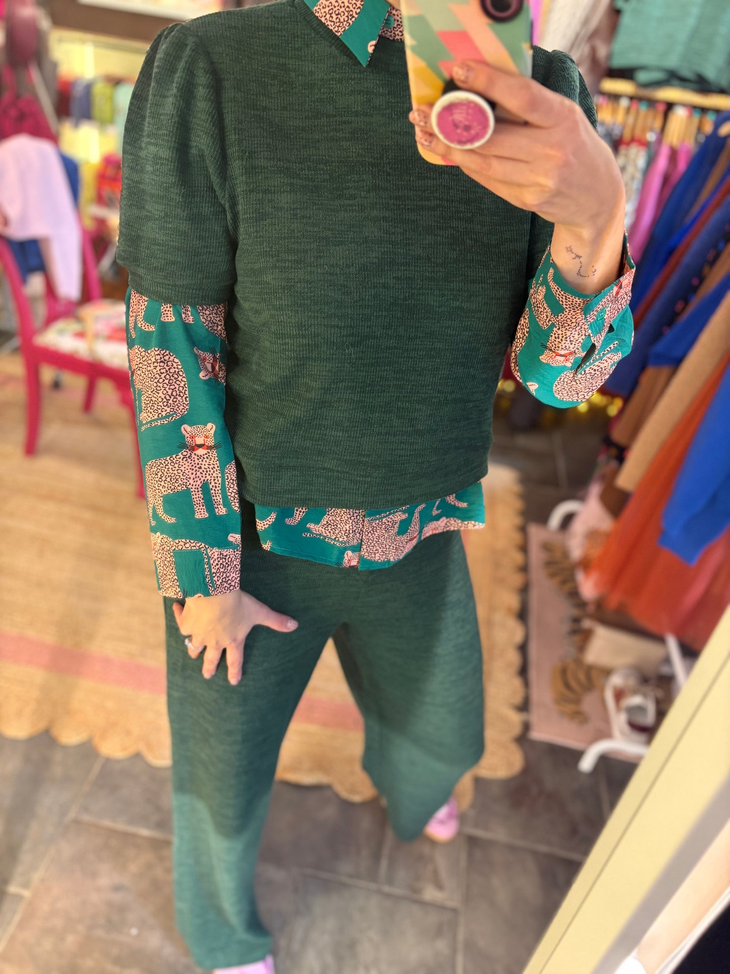 Person wearing a green outfit with a layered print blouse  in a store setting