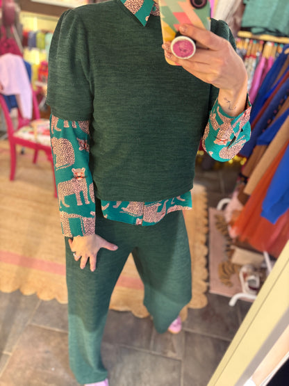 Person wearing a green outfit with a layered print blouse  in a store setting