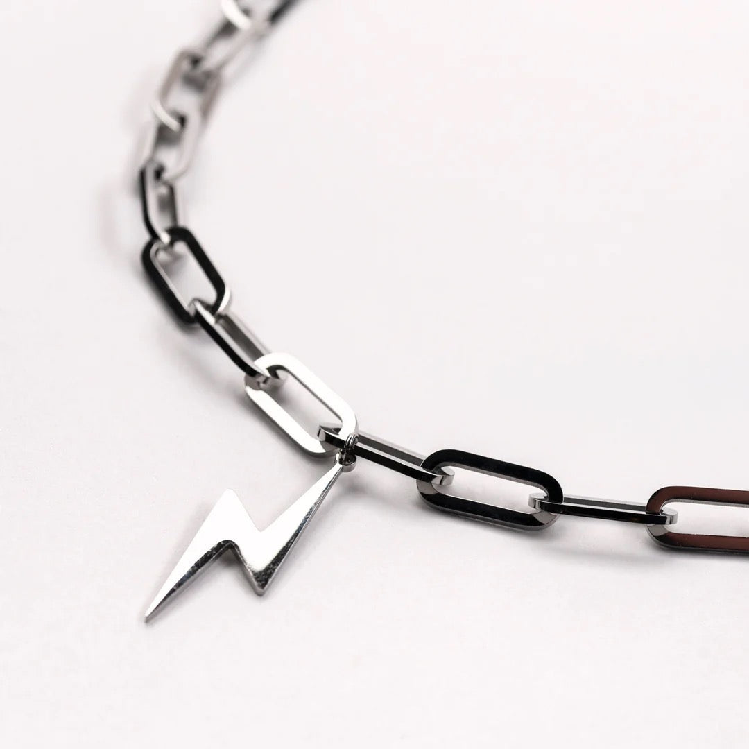Silver chain bracelet with a lightning bolt charm on a white background