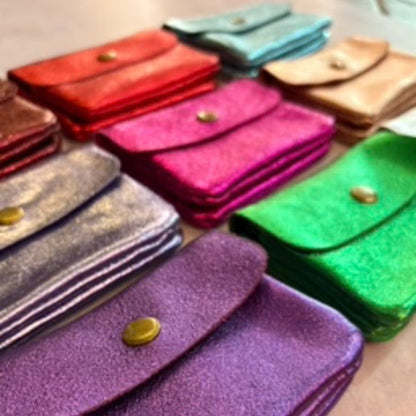Colorful leather metallic coin purses in various sizes and colors on a light surface