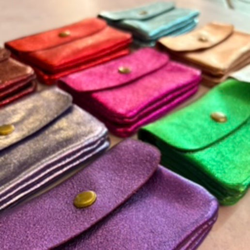 Colorful leather metallic coin purses in various sizes and colors on a light surface