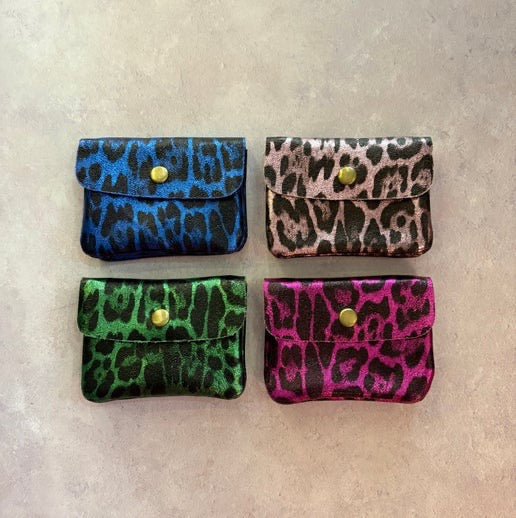 Four small pouches with metallic leopard print pattern and gold buttons on a beige background