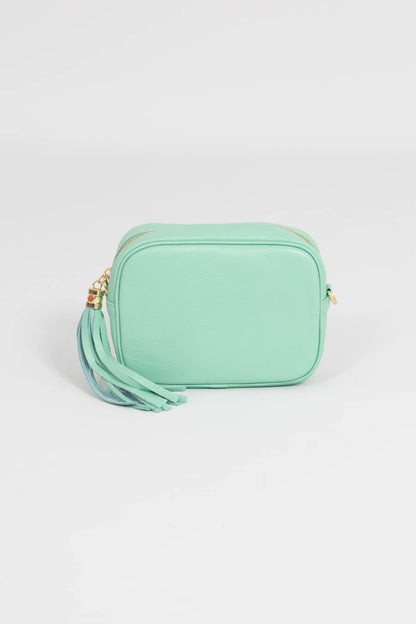 Mint green crossbody bag with a tassel on a light gray background