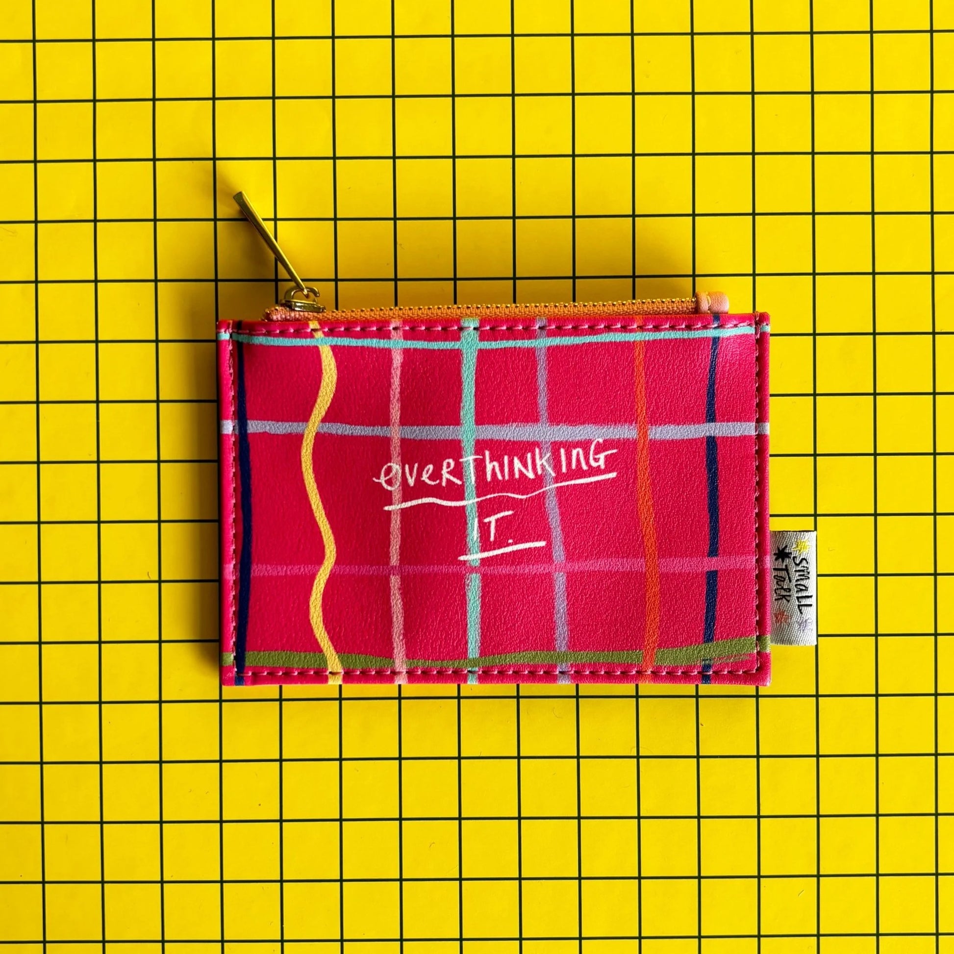 Plaid pouch with 'OVER THINKING IT' text on a yellow grid background