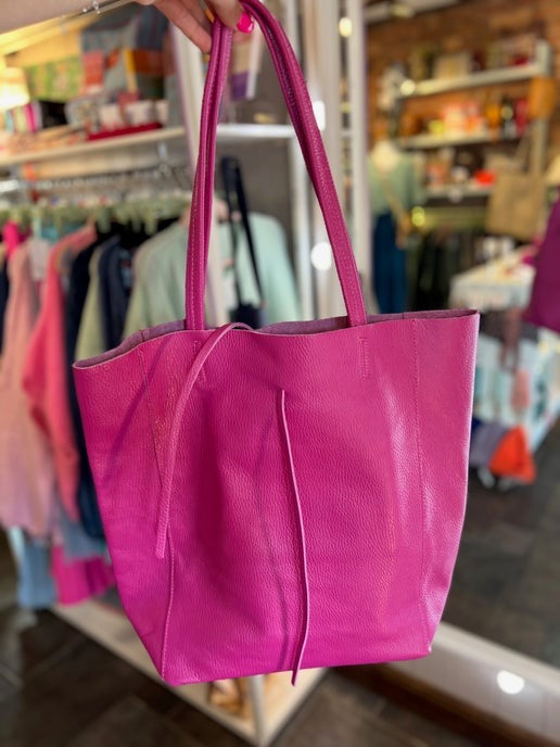 Pink tote bag held in front of a clothing store background
