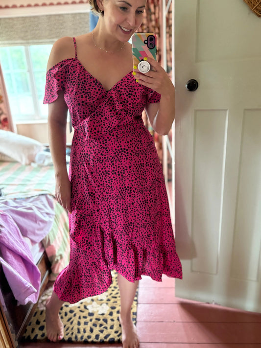Woman wearing a pink dress with black patterns in a room.
