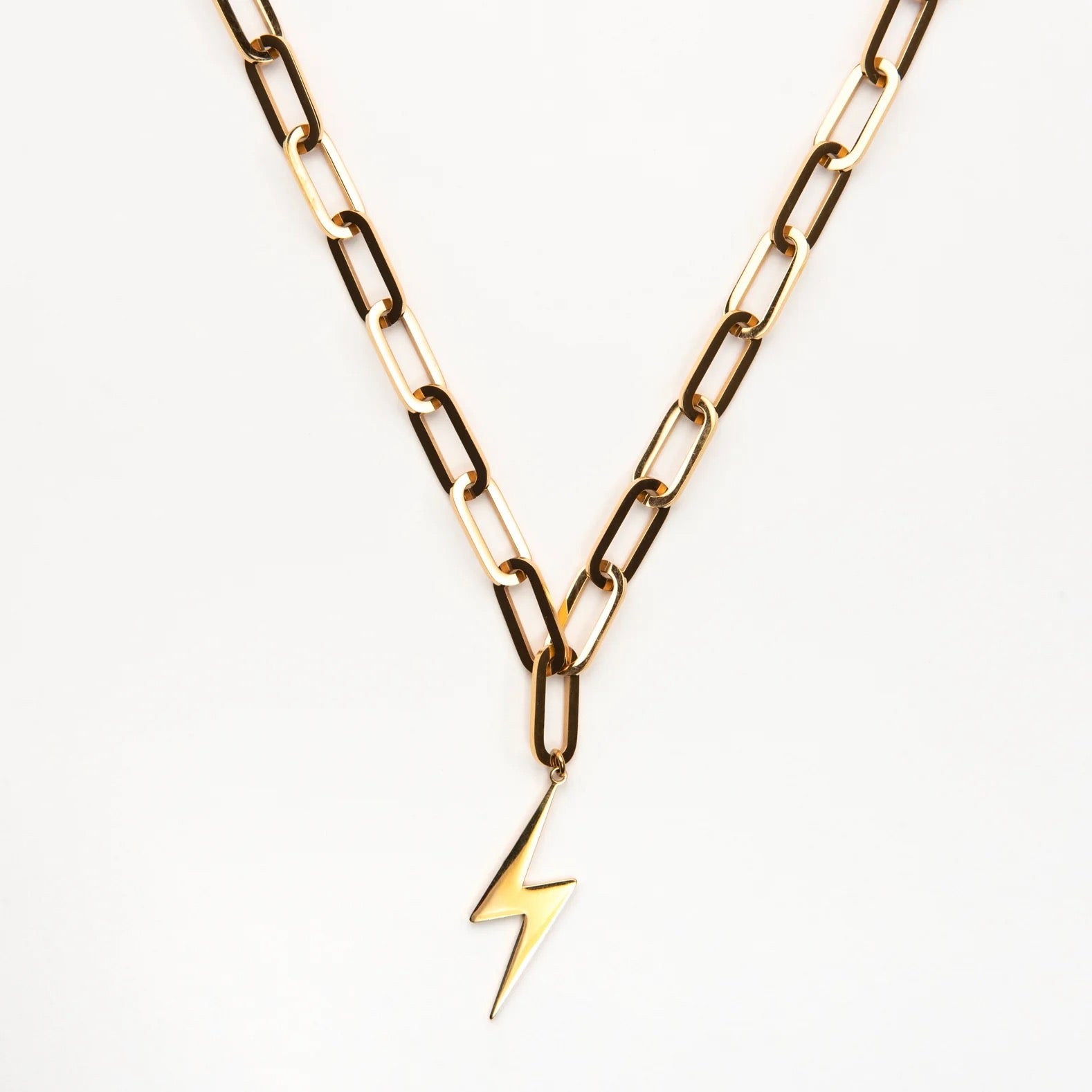 Gold chain necklace with a lightning bolt pendant on a white background