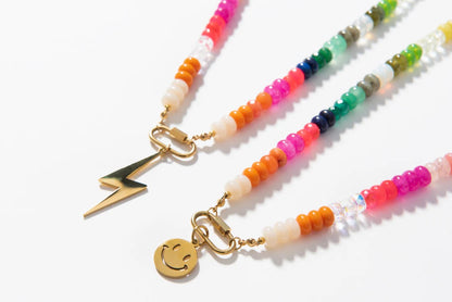 Colorful beaded necklaces with gold charms on a white background