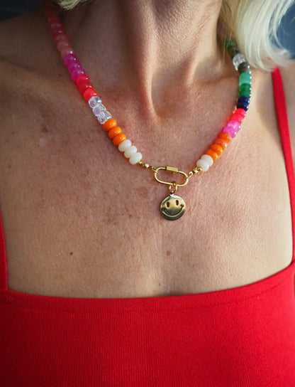 Colorful beaded necklace with a smiley face charm worn by a person in a red top.