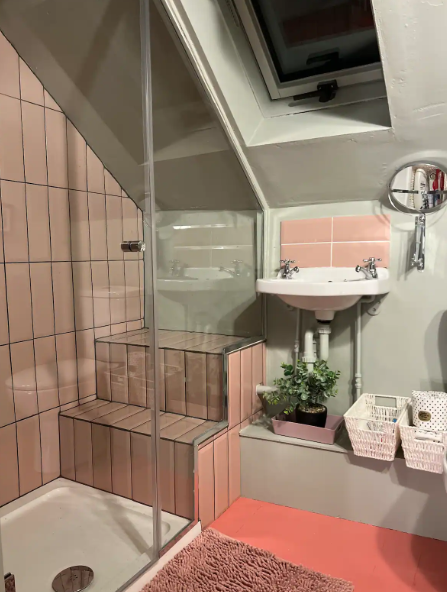 Small bathroom with pink tiles, a sink, and various fixtures.