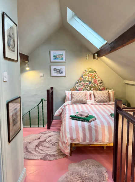 Bedroom with pink floor, striped bedspread, and floral headboard.