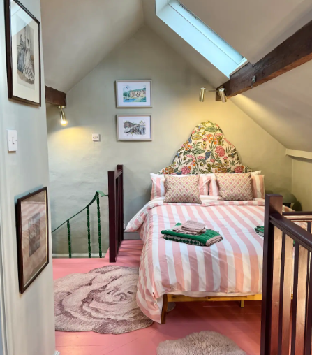 Bedroom with pink floor, striped bedspread, and floral headboard.