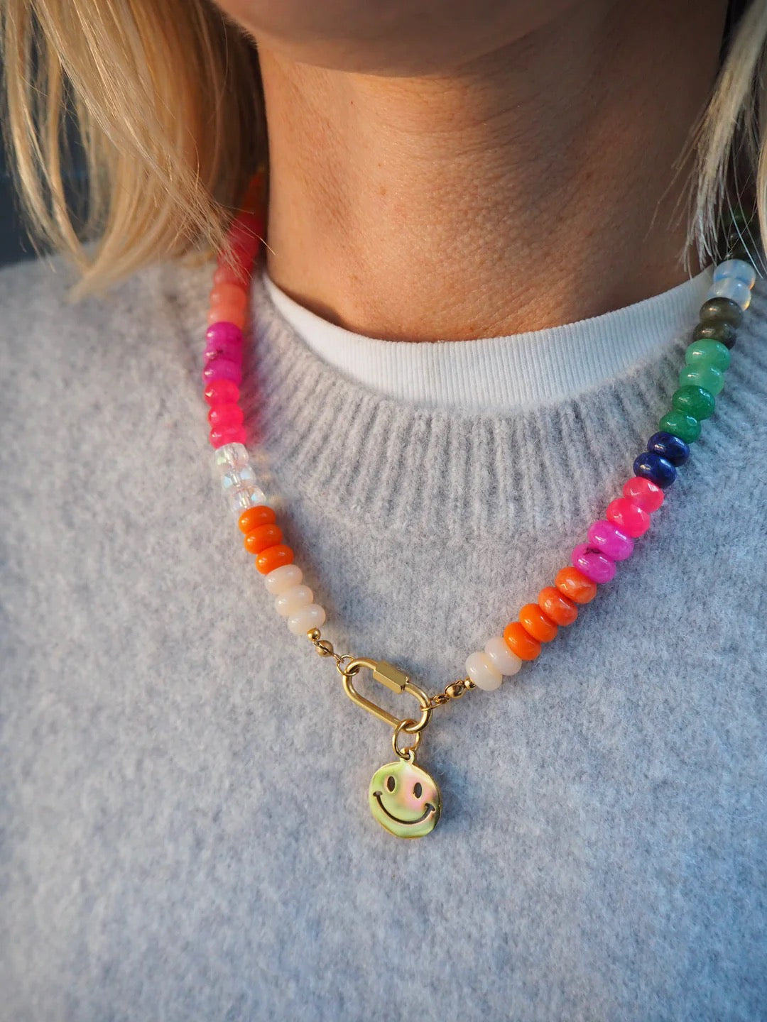 Colorful beaded necklace with a smiley face charm worn by a person.