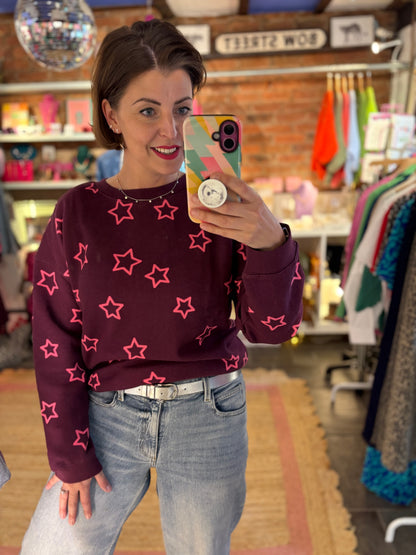 Person wearing a purple sweater with pink stars in a store setting