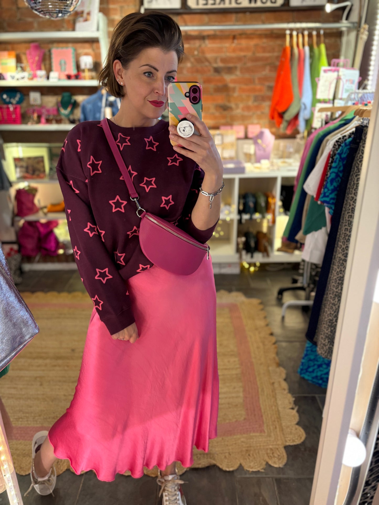 Person wearing a star-patterned sweater and pink skirt in a store.