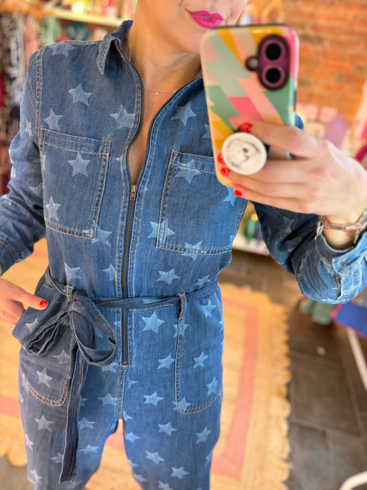 Person wearing a blue denim jumpsuit with star patterns, holding a colorful phone case.
